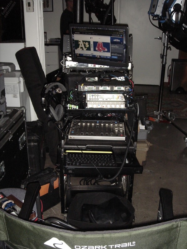 Video equipment rack and cart with a green camping chair beside it