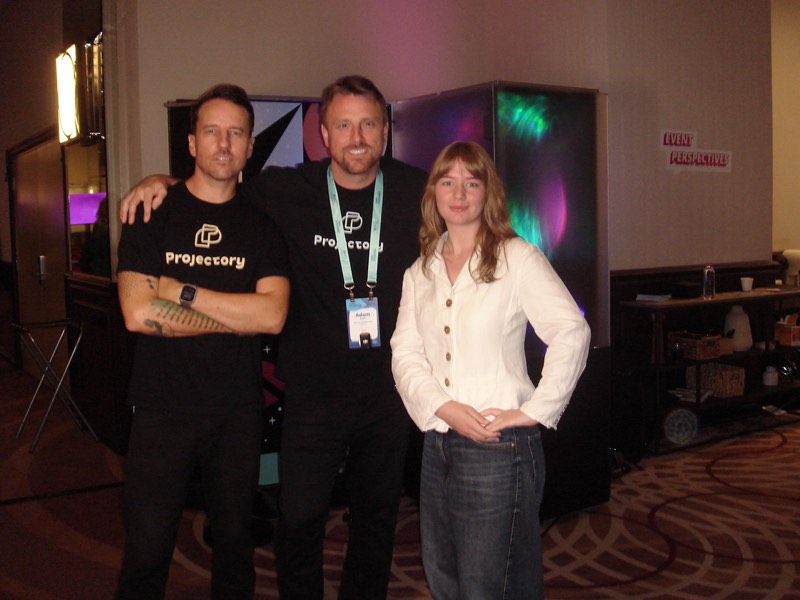 Three crew members together at an event, lanyards on